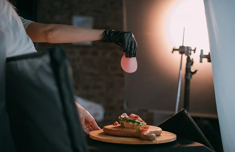 A photographer's studio set up taking an image of an open sandwich on a wooden chopping board.