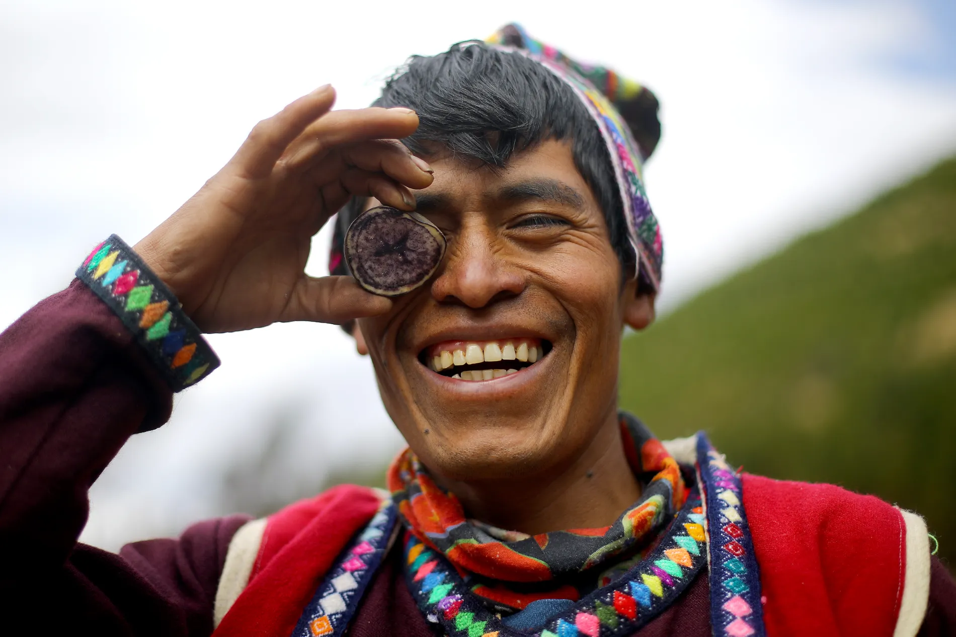 Farmer Marco Pacco smiles for the picture holding a purple potato usually used by food companies to produce snacks.